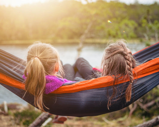 2 girls lying in a hammock outside.