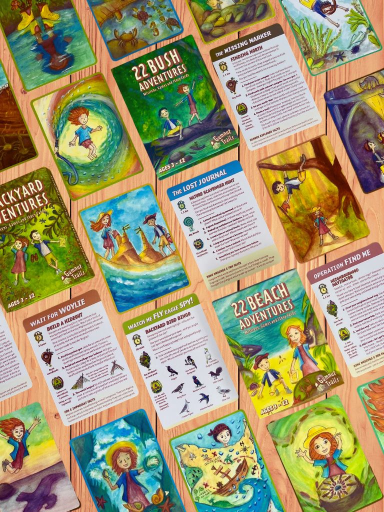 Collection of children's activity cards with various scenes and text on a wooden surface. Gumnut Trails Guides