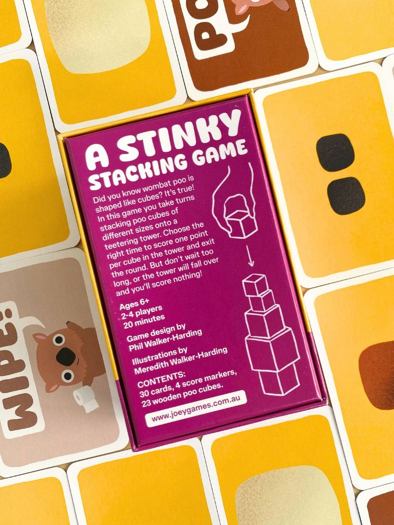 A close-up of a purple instruction card for the board game 'A Stinky Stacking Game', laid over a grid of yellow and brown stacking cubes. Wombat Poo