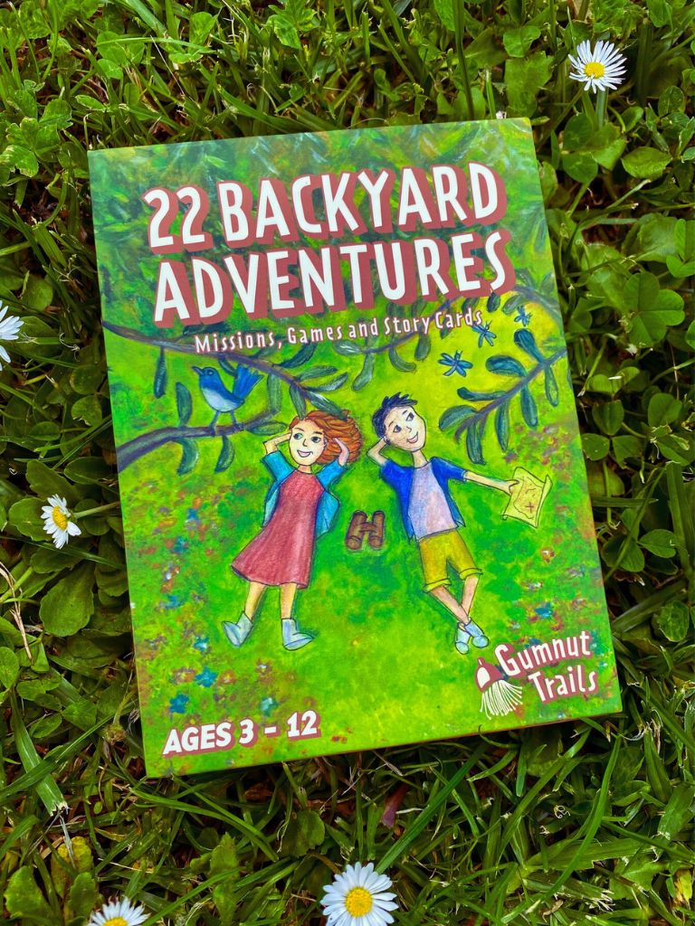 Book titled '22 Backyard Adventures' on grass with flowers. Gumnut Trails Guide