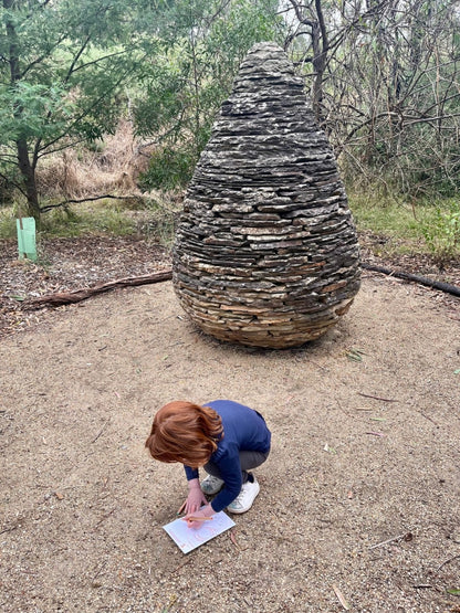 Child drawing next to sculpture