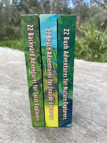 Three books titled '22 Backyard Adventures', '22 Beach Adventures for Local Explorers', and '22 Bush Adventures for Nature Explorers' on a wooden surface with a natural background.