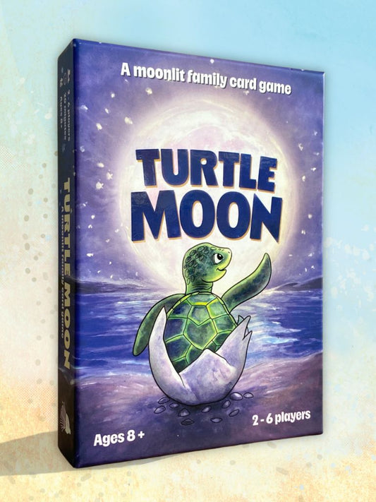 Turtle Moon family card game box shown at a slight angle against a soft light blue and beige gradient background. The box art features a green sea turtle hatching from a white shell under a glowing moon, with the title 'TURTLE MOON' in large blue letters.